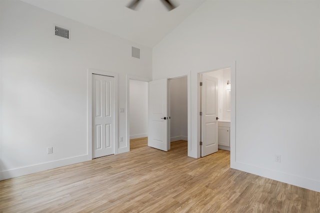 unfurnished bedroom with ceiling fan, high vaulted ceiling, connected bathroom, light hardwood / wood-style floors, and a closet