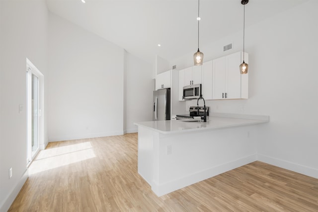 kitchen featuring kitchen peninsula, pendant lighting, white cabinets, and stainless steel appliances