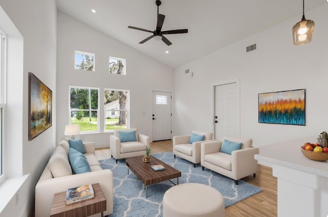 living room featuring ceiling fan, high vaulted ceiling, and light hardwood / wood-style flooring