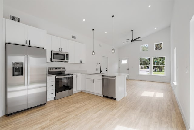 kitchen featuring ceiling fan, kitchen peninsula, decorative light fixtures, white cabinets, and appliances with stainless steel finishes