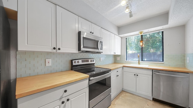 5811 Atlantic Blvd Unit 57, Jacksonville, FL 32207 - kitchen featuring appliances with stainless steel finishes, butcher block counters, a textured ceiling, white cabinets, and backsplash