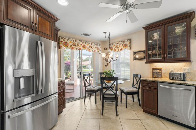 19 San Rafael Ct, Palm Coast, FL 32137 - kitchen featuring stainless steel appliances, dark brown cabinets, backsplash, light tile patterned flooring, and light stone counters