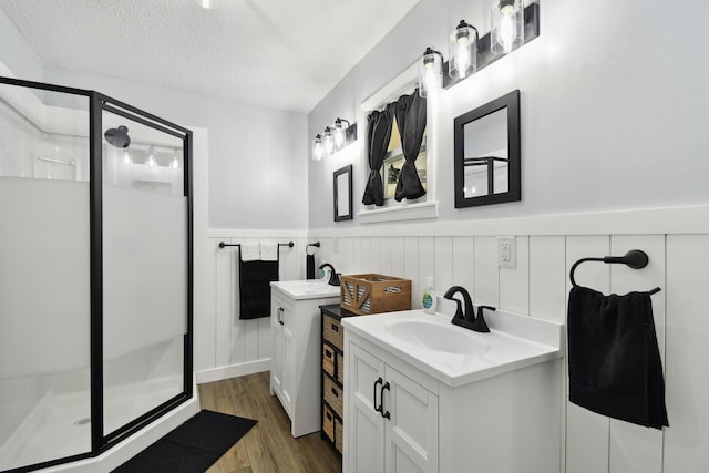 bathroom with hardwood / wood-style flooring, vanity, a shower with shower door, and a textured ceiling