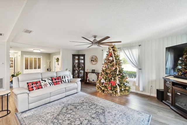 living room featuring ceiling fan, a textured ceiling, and light hardwood / wood-style flooring