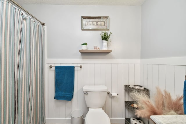 bathroom with a shower with shower curtain, toilet, and a textured ceiling