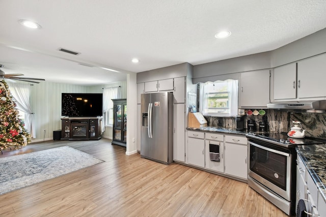 kitchen featuring light wood-type flooring, backsplash, a textured ceiling, stainless steel appliances, and ceiling fan