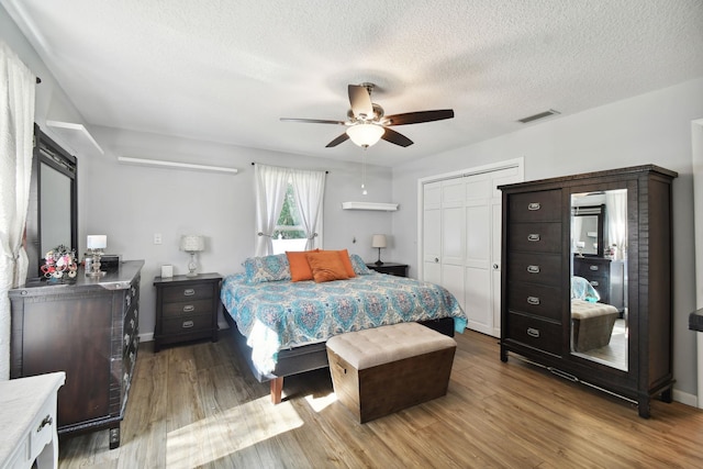 bedroom with ceiling fan, a closet, wood-type flooring, and a textured ceiling