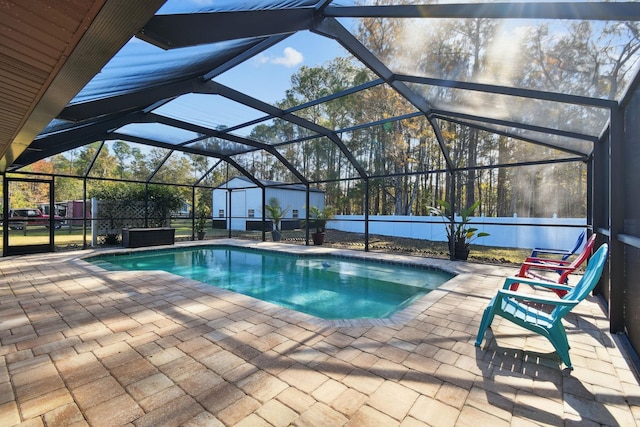 view of pool featuring glass enclosure, a patio, and a storage shed