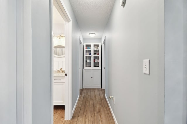 hallway featuring a textured ceiling and light wood-type flooring