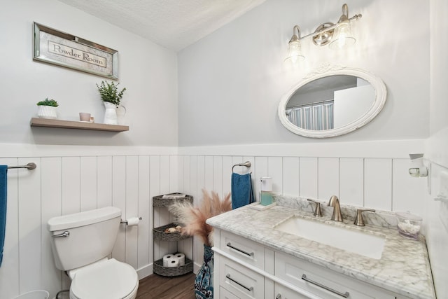 bathroom with toilet, vanity, a textured ceiling, and hardwood / wood-style flooring