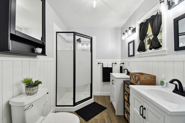 bathroom with a textured ceiling, toilet, a shower with door, vanity, and hardwood / wood-style flooring