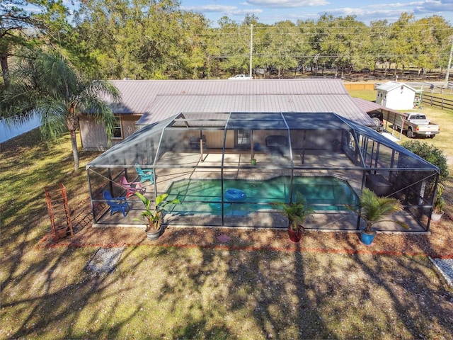 view of swimming pool featuring glass enclosure, a patio area, and a shed