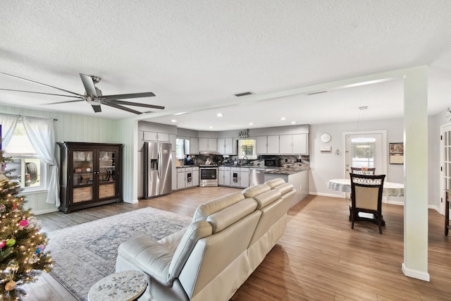 living room with ceiling fan, light hardwood / wood-style flooring, a textured ceiling, and sink