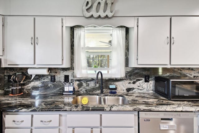 kitchen with sink, stainless steel dishwasher, decorative backsplash, dark stone countertops, and white cabinetry