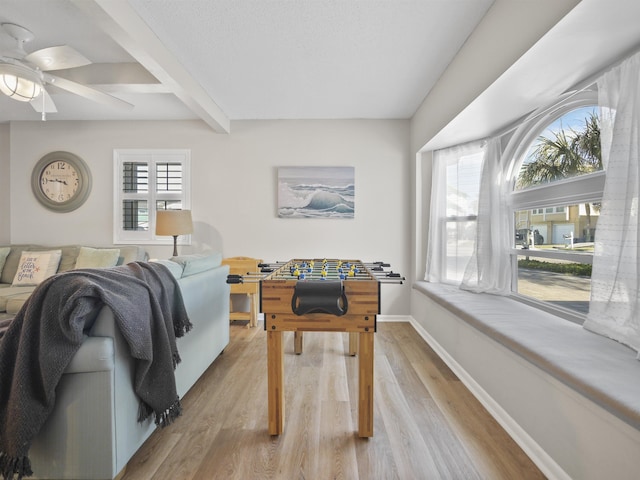 game room with a wealth of natural light, beamed ceiling, light wood-style flooring, and baseboards