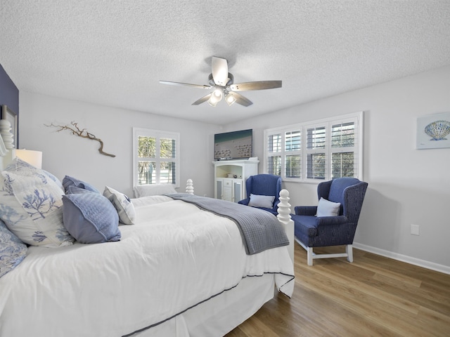 bedroom with hardwood / wood-style flooring, a textured ceiling, ceiling fan, and multiple windows