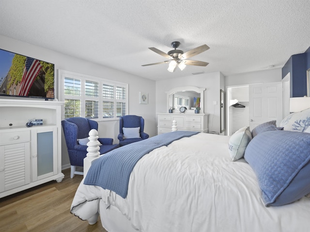 bedroom with multiple windows, ceiling fan, a textured ceiling, and wood finished floors