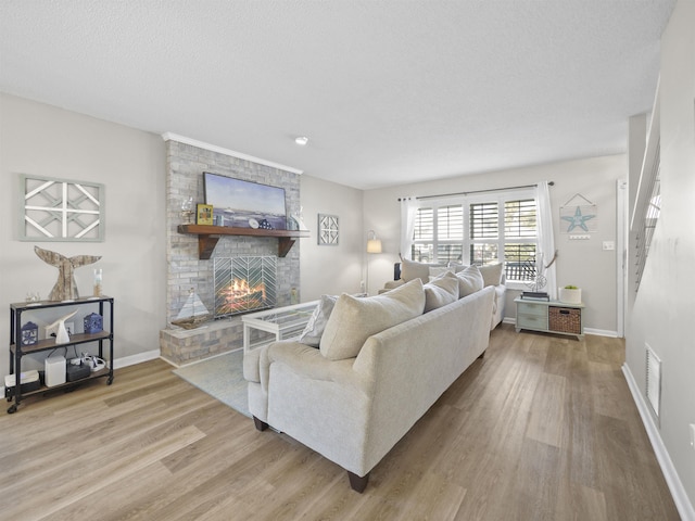 living room with a brick fireplace, a textured ceiling, and hardwood / wood-style floors