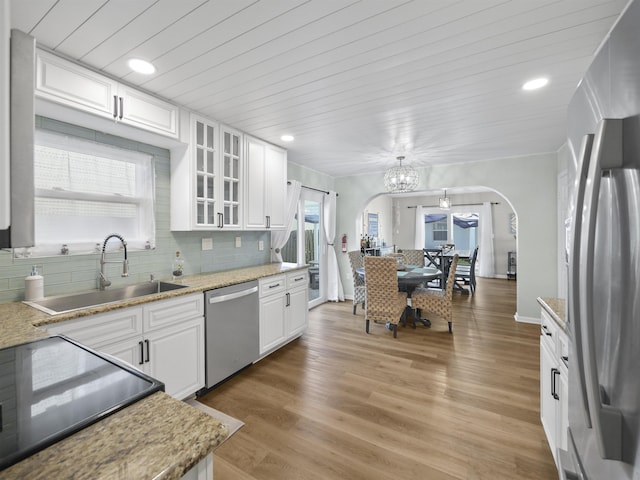 kitchen featuring stainless steel appliances, arched walkways, a sink, and plenty of natural light