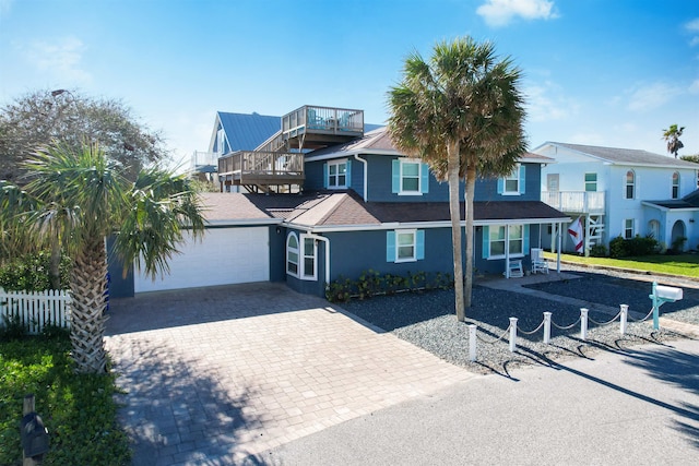 view of front of property with decorative driveway, stucco siding, an attached garage, fence, and a balcony