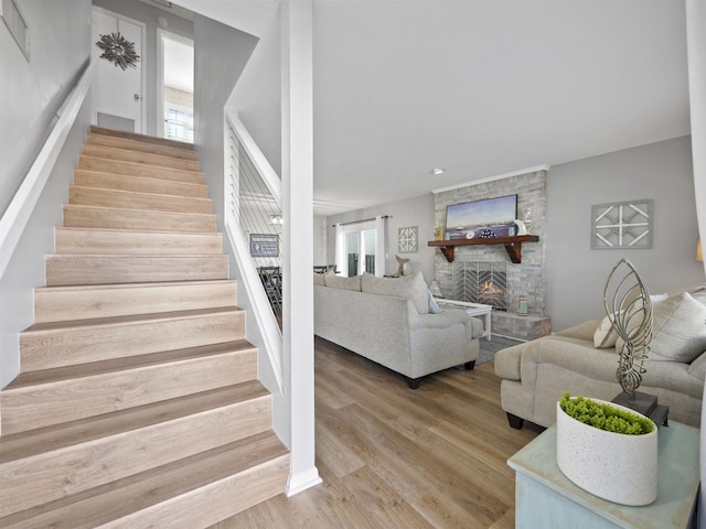 staircase with hardwood / wood-style flooring and a stone fireplace