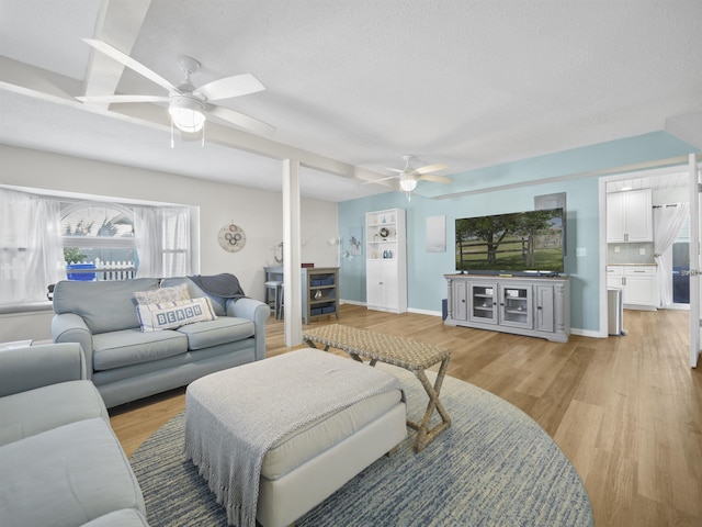 living room with light wood-style floors, ceiling fan, a textured ceiling, and baseboards