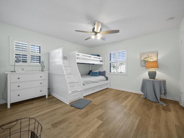 bedroom featuring light wood finished floors, a ceiling fan, and baseboards