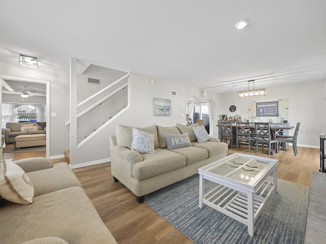 living room with stairway, wood finished floors, visible vents, and baseboards