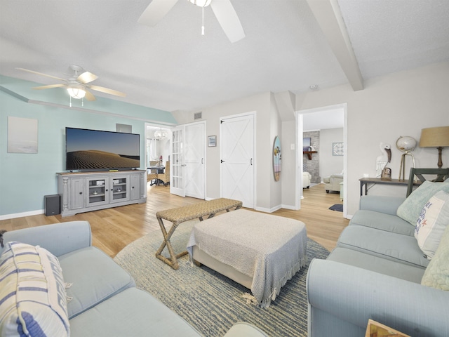 living room featuring ceiling fan, light wood-type flooring, and beamed ceiling