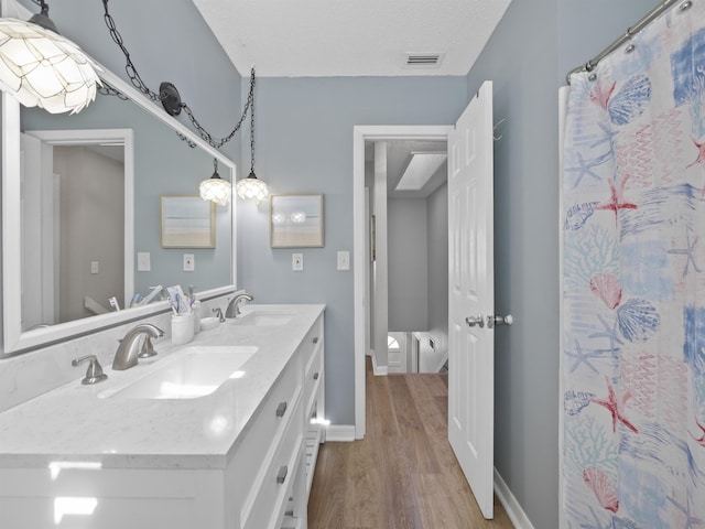 bathroom with vanity, a textured ceiling, hardwood / wood-style floors, and a shower with curtain