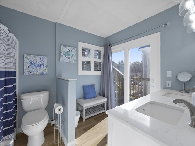 full bathroom with double vanity, wood finished floors, a sink, and toilet