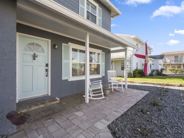 entrance to property with covered porch and stucco siding