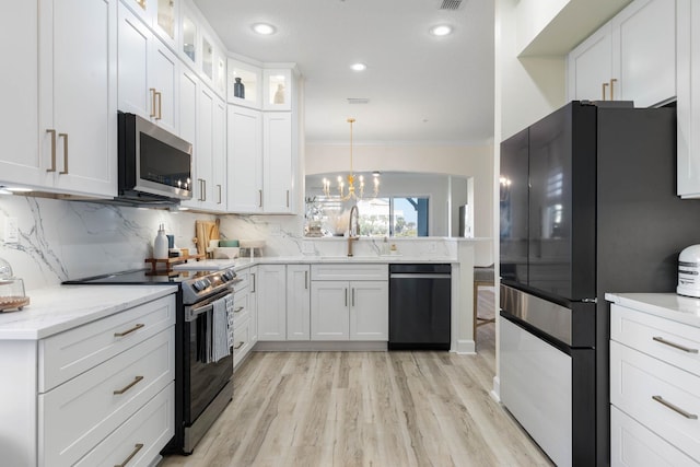 kitchen with sink, appliances with stainless steel finishes, white cabinets, and decorative light fixtures