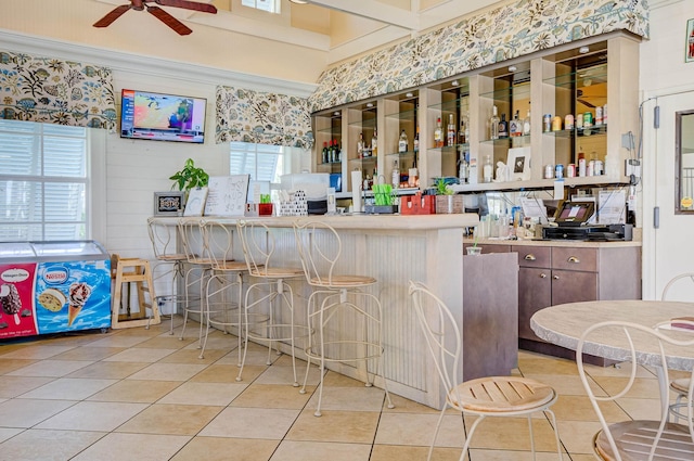 kitchen featuring a kitchen bar, ceiling fan, light tile patterned floors, and kitchen peninsula