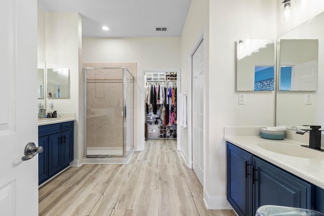 bathroom featuring hardwood / wood-style flooring, a shower with shower door, and vanity