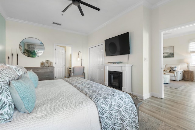 bedroom featuring light wood-type flooring, a closet, ceiling fan, and ornamental molding