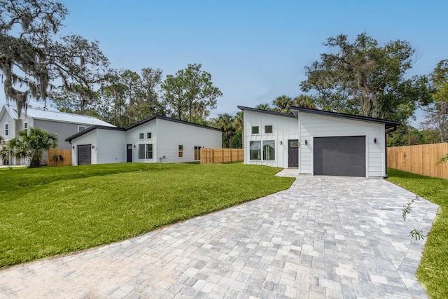 view of front facade with a front yard, decorative driveway, fence, and a garage