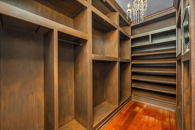 walk in closet with a chandelier and dark wood-type flooring