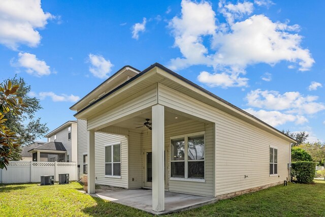 rear view of house with ceiling fan, cooling unit, a patio area, and a yard