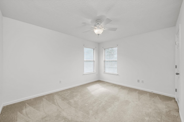 spare room featuring ceiling fan, light colored carpet, and a textured ceiling