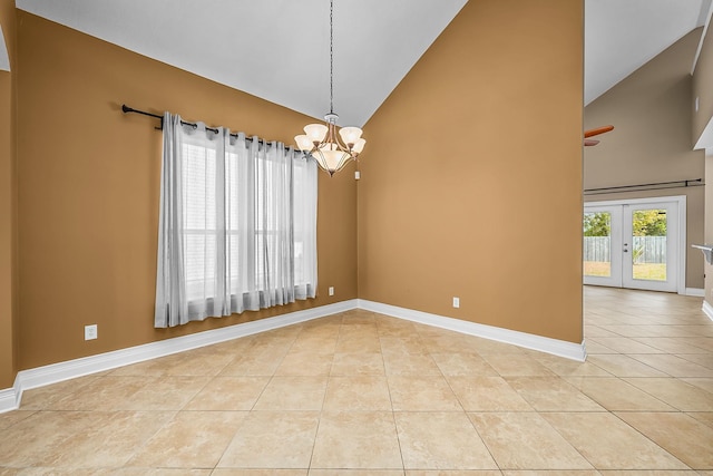 tiled empty room featuring french doors, an inviting chandelier, and high vaulted ceiling