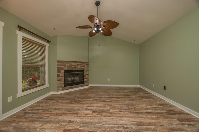 unfurnished living room with wood-type flooring, a stone fireplace, ceiling fan, and lofted ceiling