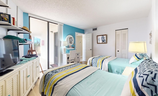 bedroom featuring a wall of windows, a closet, a textured ceiling, and light hardwood / wood-style flooring