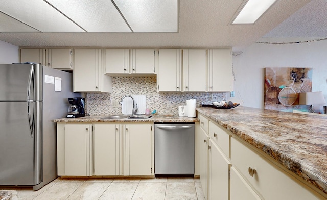 kitchen featuring cream cabinets, sink, light tile patterned floors, tasteful backsplash, and stainless steel appliances