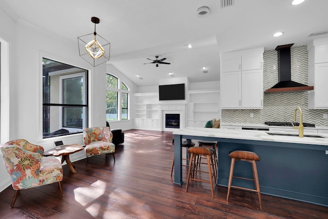 545 Sebastian Sq, Saint Augustine, FL 32095 - kitchen featuring wall chimney range hood, white cabinets, dark wood finished floors, light stone countertops, and decorative light fixtures