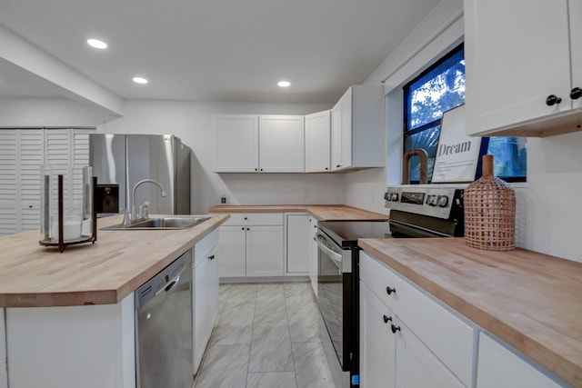 235 N Whitney St, Saint Augustine, FL 32084 - kitchen featuring butcher block countertops, stainless steel appliances, light marble finish flooring, recessed lighting, and white cabinetry