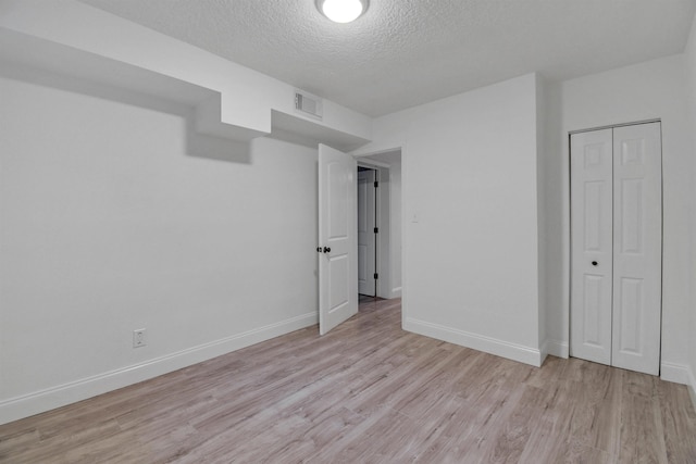 235 N Whitney St, Saint Augustine, FL 32084 - unfurnished bedroom with light wood-style flooring, a textured ceiling, and a closet
