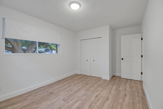 235 N Whitney St, Saint Augustine, FL 32084 - unfurnished bedroom with light wood-style floors, a textured ceiling, and a closet