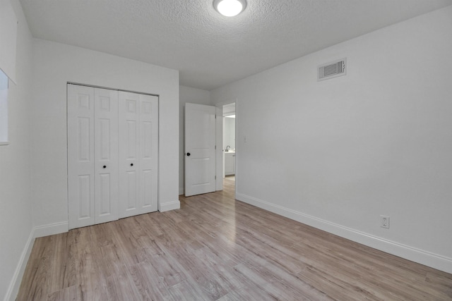 235 N Whitney St, Saint Augustine, FL 32084 - unfurnished bedroom with light wood finished floors, a textured ceiling, and a closet