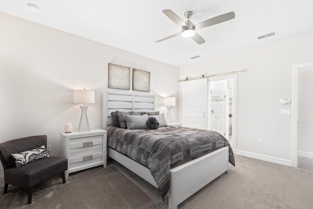 carpeted bedroom featuring ceiling fan, a barn door, and connected bathroom